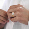 Gold statement ring on hand, featuring square center diamond cluster and pavé band.