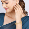 Gold bangle bracelet on wrist with openwork lattice and clear stone details