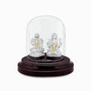 Silver Lakshmi and Ganesha idol with gold accents under clear glass dome.