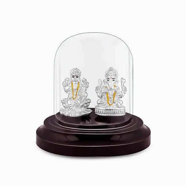 Silver Lakshmi and Ganesha idol with gold accents under clear glass dome.