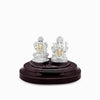 Silver Lakshmi and Ganesha idol under clear glass dome on dark base.