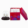 Silver Lakshmi and Ganesha idol under glass dome with red gift box.
